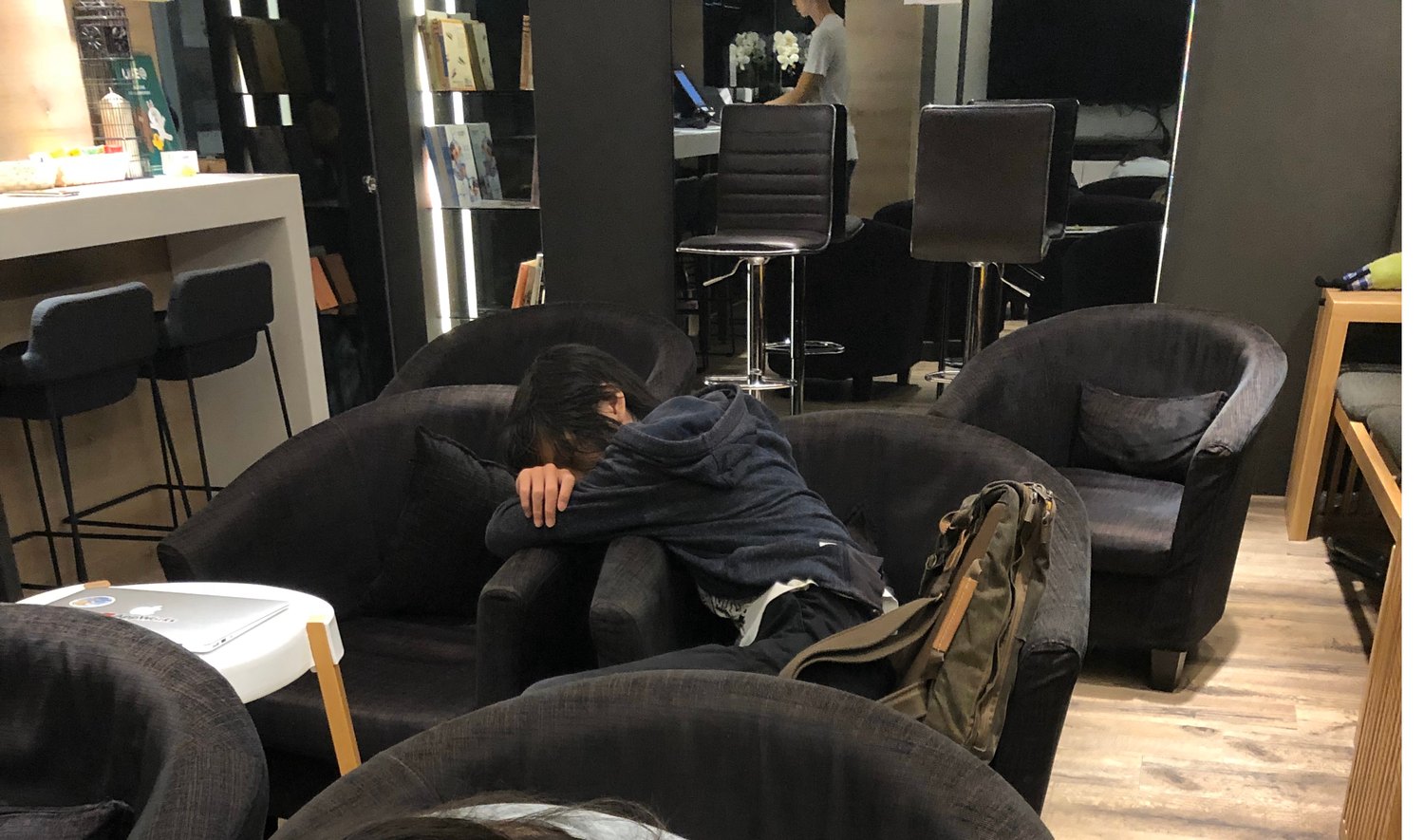 一個孩子累到趴在青旅的扶手椅上睡著,旁邊放著背包,不遠處的桌上還開著筆電。