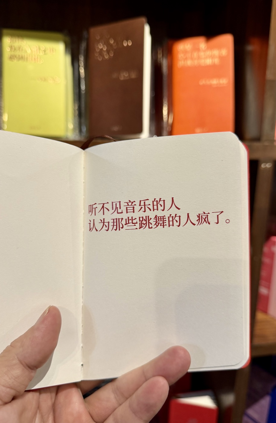 青岛良友书坊拍的笔记本，红字写着「听不见音乐的人，认为那些跳舞的人疯了。」